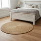 Bedroom with wooden bed frame, round woven rug, and lamp.