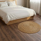 Bedroom with wooden bed frame, white bedding, and round woven rug on wooden floor.