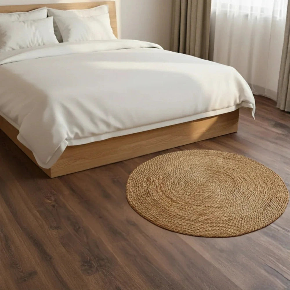 Bedroom with wooden bed frame, white bedding, and round woven rug on wooden floor.