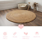 Round braided jute rug on a wooden floor with a small wooden stool and pet bed in the background.