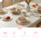 Breakfast table with white wicker placemats, bowls of granola, fruit, and tea, featuring pink icons and product text.