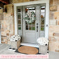 Front door of a house with a wreath and potted plants, stone wall background