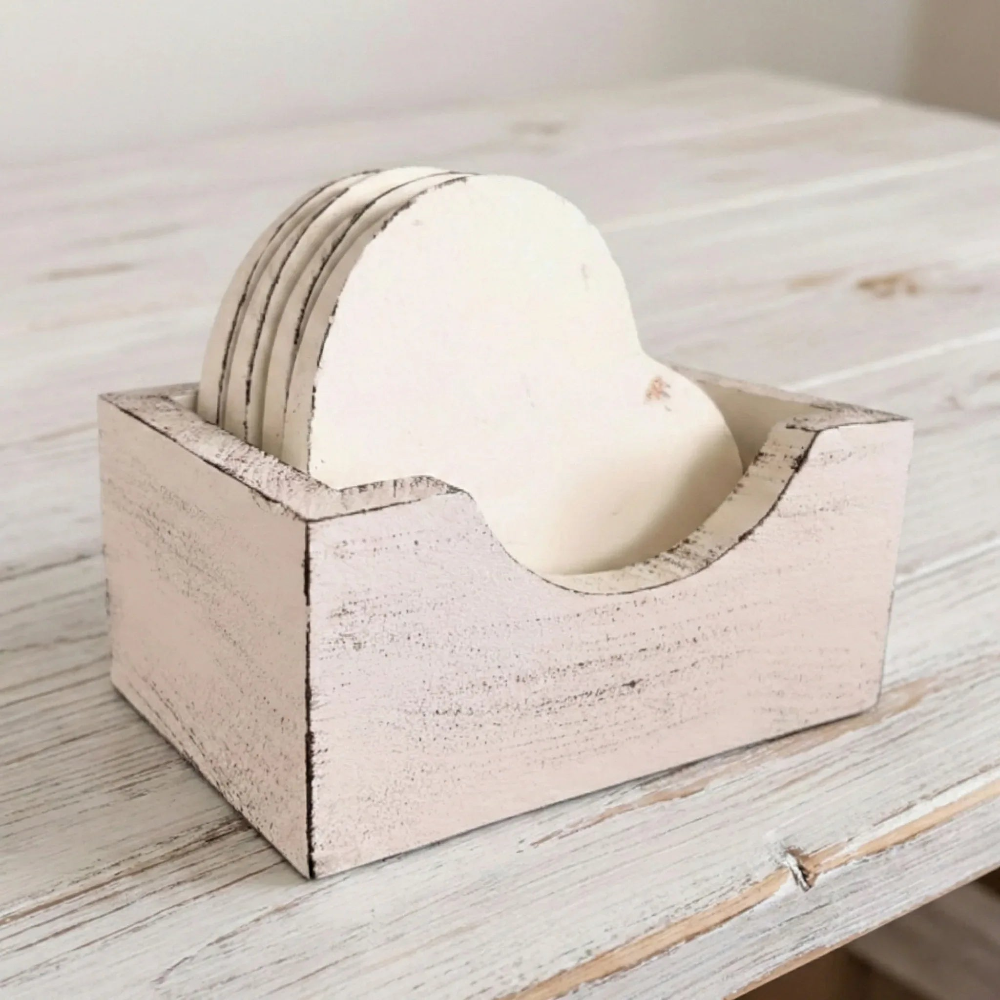 Four heart-shaped white coasters in a distressed light pink wooden holder on a white wood surface.