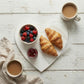 Heart-Shaped Serving Board used in breakfast setup with croissants, berries, and coffee on wooden surface