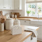 Kitchen counter with flour and sugar canisters, a heart-shaped tissue holder, and a towel in a bright kitchen.