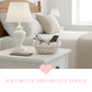 Living room scene with a white lamp, remote control, glasses in a Cottage Round Wicker Basket and phone on a coffee table.