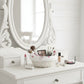 Makeup vanity with mirror, Round Wicker Basket of brushes, and various makeup items on a white dresser.