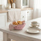 Mini Wicker Basket used as dining table centerpiece holding croissants beside cup and saucer in kitchen setting