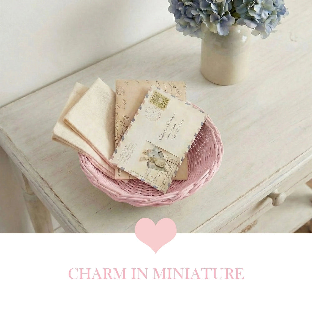 Mini Wicker Basket pink woven holding vintage books and postcards on wooden table with floral vase