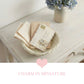 Mini Wicker Basket styled with vintage books and postcards on wooden table with floral background decor