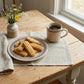 Plate of nashader biscuits and a cup of coffee on a wooden table with a vase of flowers.