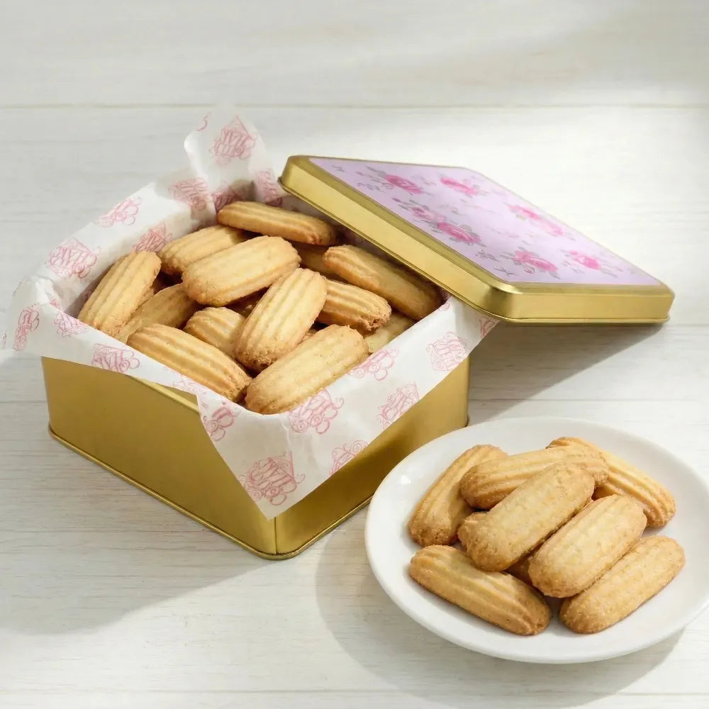 Open gold tin with nashader cookies on a white surface