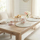 Wooden table set with teacup, teapot, and decorative items in a bright room.