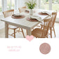 Dining table set with chairs, placemats, and a vase of flowers in a bright room.