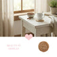 White table with a cup, bowl, and plant in a softly lit room.