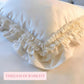 Close-up of an off-white pillow with layered ruffled edges and pink text reading timeless durability.