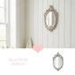 Ornate oval vintage mirror hanging on white shiplap wall next to a window, above a pink heart and graphic text.
