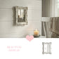 Ornate white rectangular mirror on a shiplap wall beside a lit candle, with a small mirror icon and heart below.