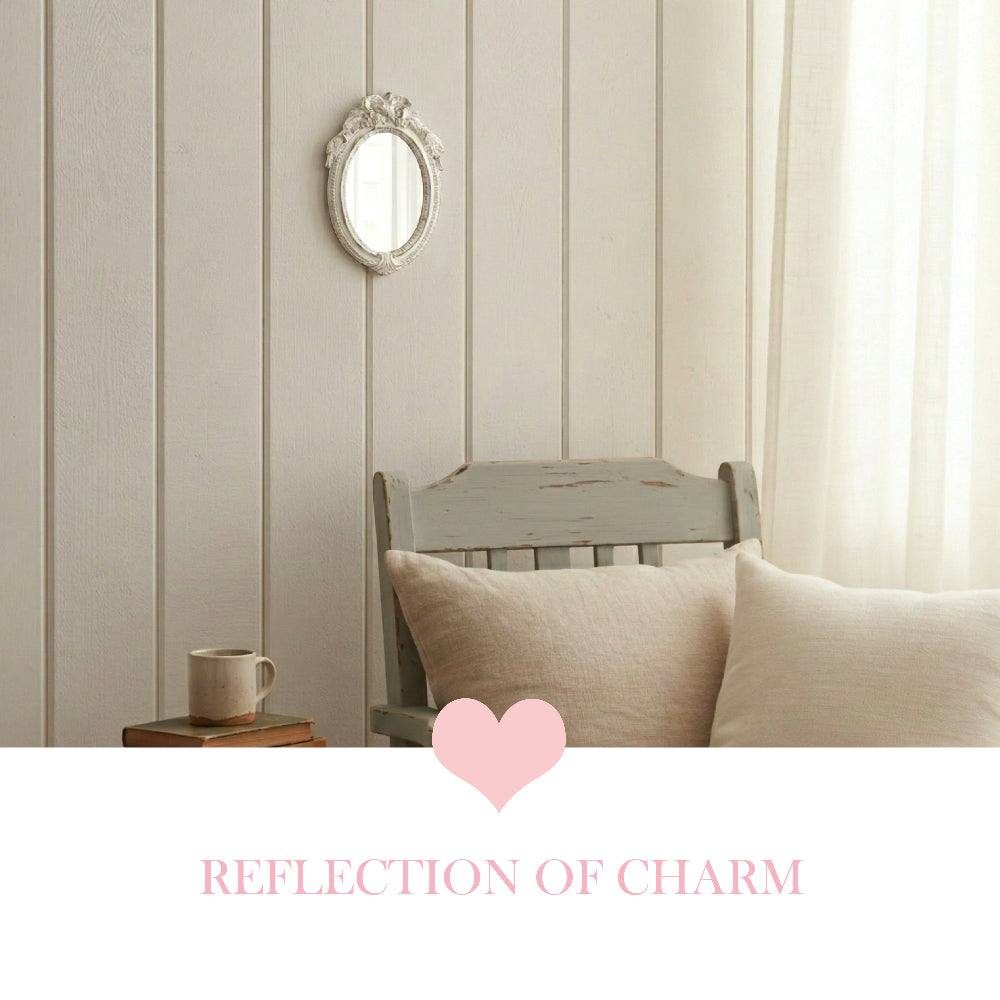 Small oval antique white mirror on a cream paneled wall above a distressed wooden chair with beige pillows.