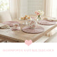 Pale pink round halfa grass placemats set on a rustic wooden dining table for afternoon tea, featuring a floral teapot, scones, and blush roses in a bright farmhouse setting.