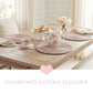 Tea set on a wooden table with woven placemats and a pink heart graphic.
