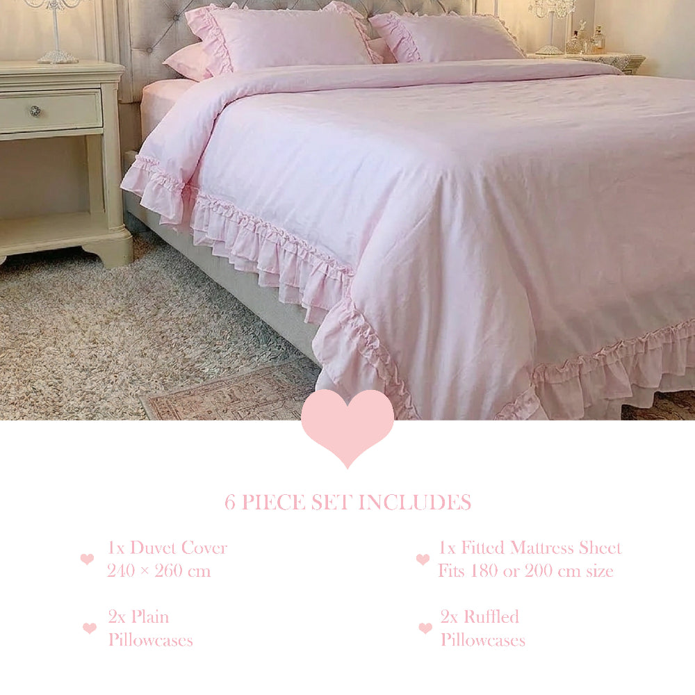Pale pink ruffled bedding on a white bed frame with a matching ruffled cushion and two standard pillows.