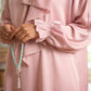Person wearing a pink outfit holding a turquoise prayer beads