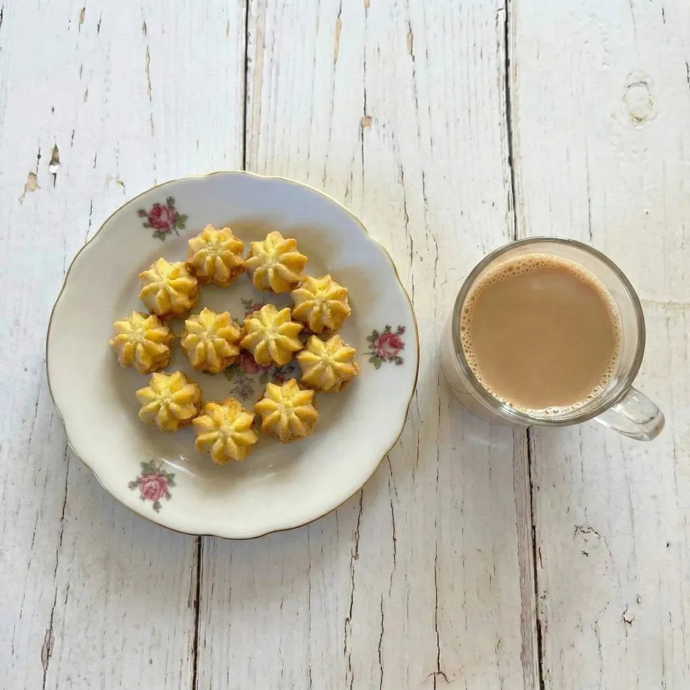 Decorative plate with petit four cookies and a glass of coffee on a wooden surface
