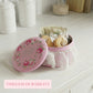 Pink cookie tin with floral design on a white surface, containing cookies and tea bags.