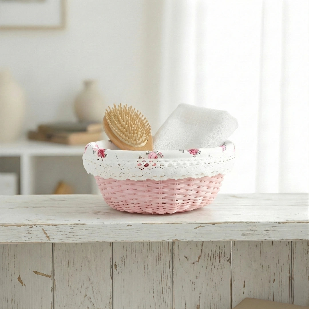 Pink Cottage Round Wicker Basket with a white lid on a wooden surface, containing a brush and a white container.