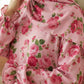 Close-up of a pink floral Isdal Prayer dress with ruffled sleeves.