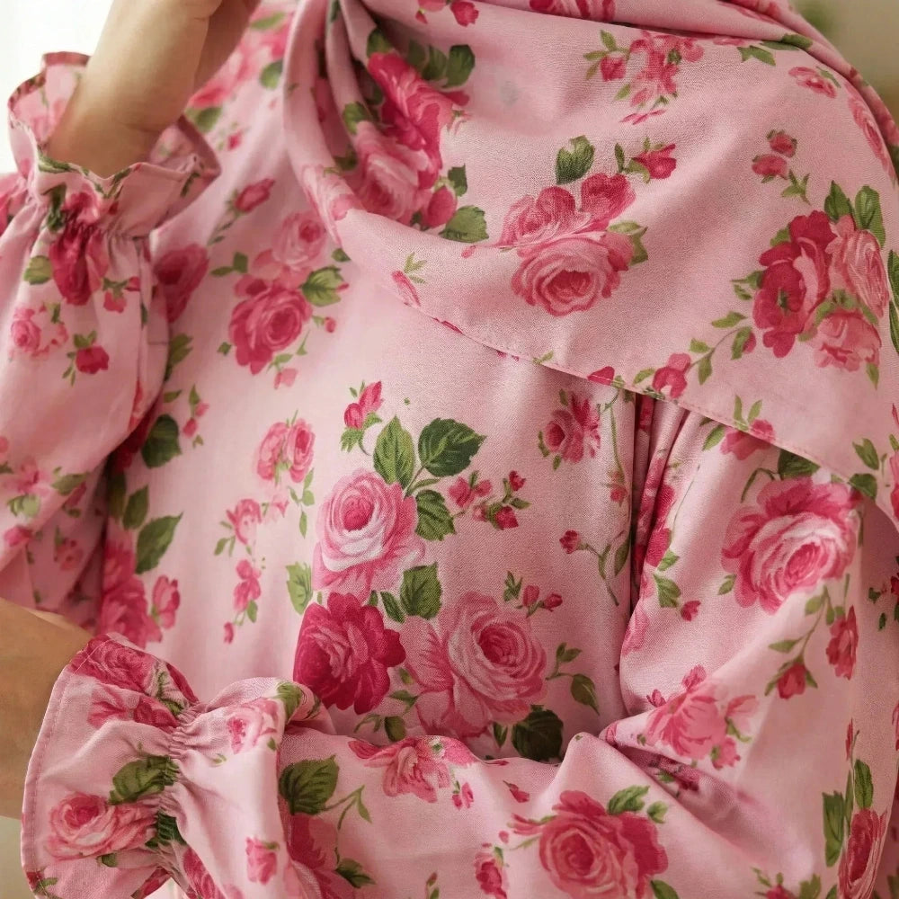 Close-up of a pink floral Isdal Prayer dress with ruffled sleeves.