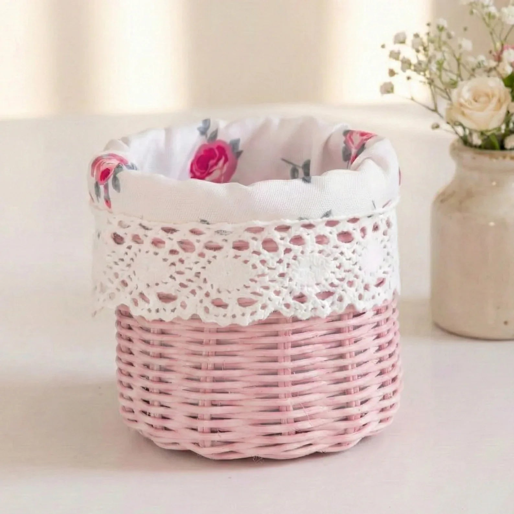 Small pink wicker basket with a white rose-patterned fabric lining and crochet lace trim on a white surface.