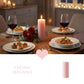 Lit pink pillar candle on a dining table with pasta, appetizers, red wine, and roses in a dimly lit room.