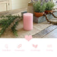 Lit pink pillar candle on a rustic wooden tray with lavender sprigs, rose petals, and a white heart stone.