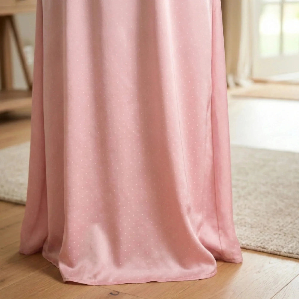 A draped polka dot Isdal Prayer dress fabric, featuring a subtle white polka dot pattern, shown hanging over a bed in a softly lit bedroom setting.