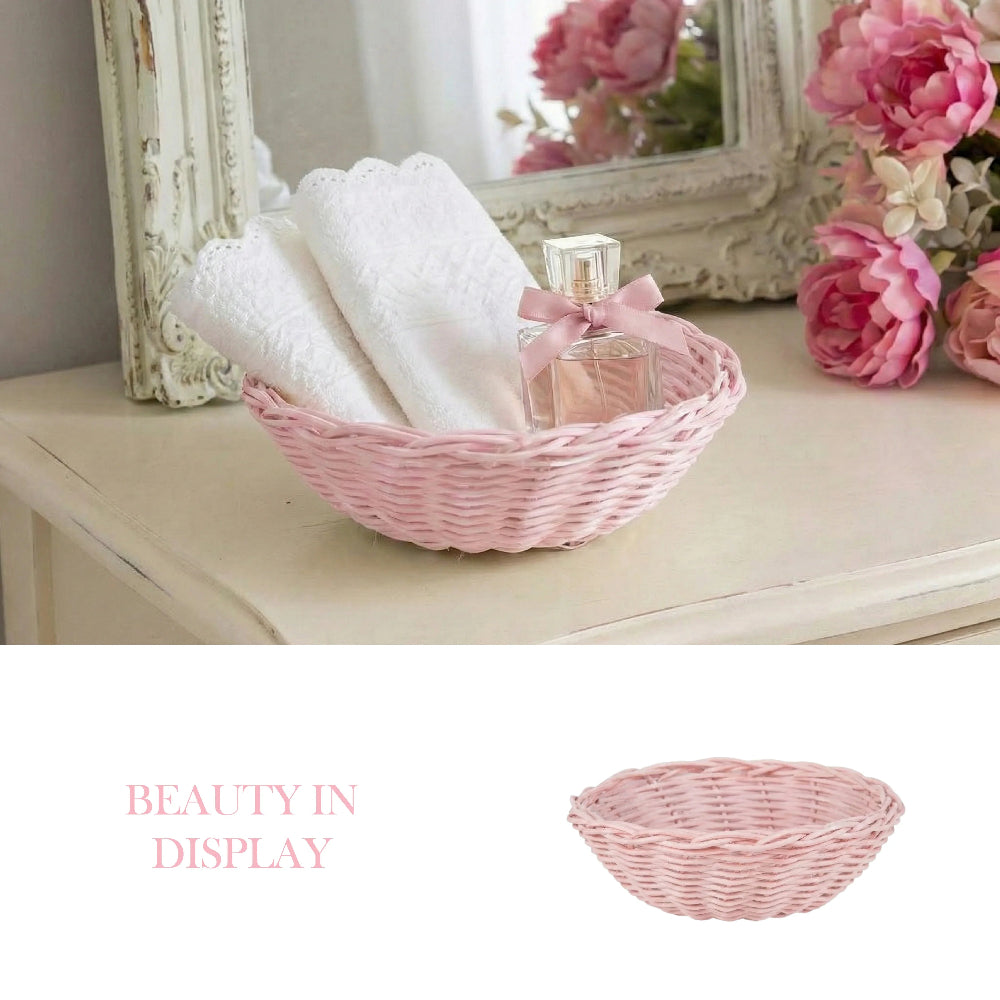 Pink wicker basket with white towels and perfume on a white vanity next to pink flowers and a vintage mirror.