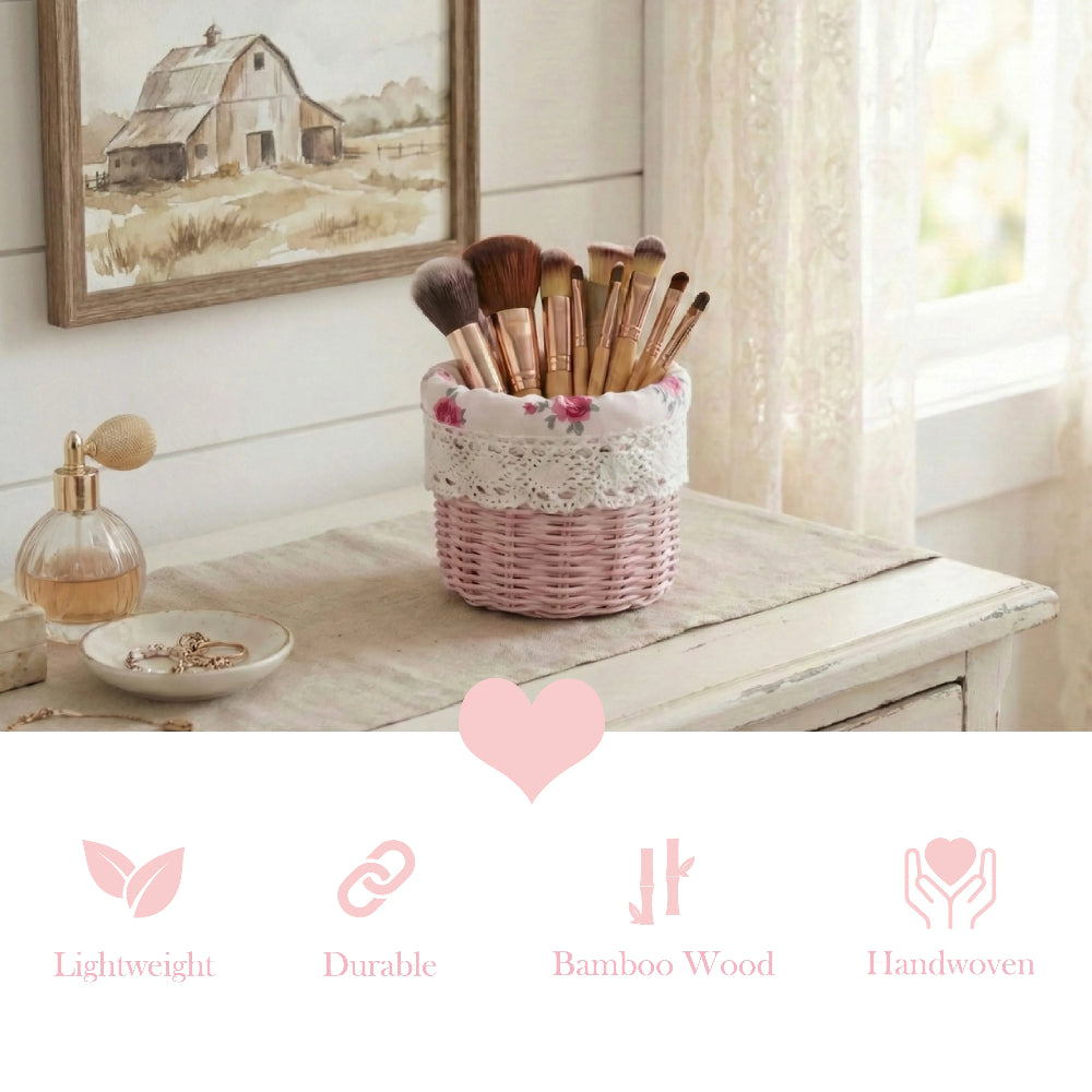 Small pink wicker basket holding makeup brushes on a white table next to perfume, jewelry, and barn artwork.