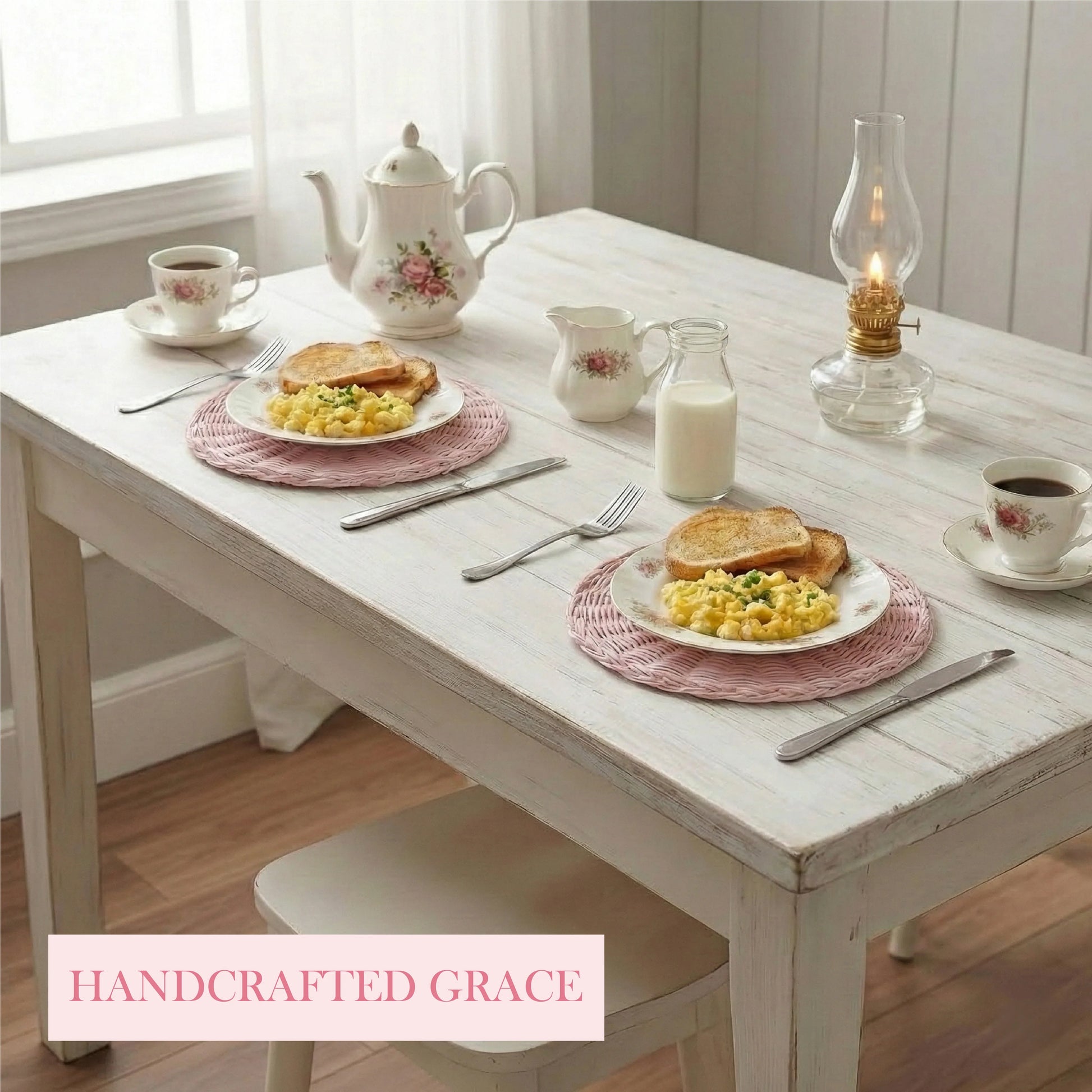 Breakfast table with pink wicker placemats, eggs, toast, tea, and an oil lamp on a distressed white wooden table.