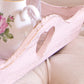 Close-up of a pink wooden tray with a floral teacup in the background