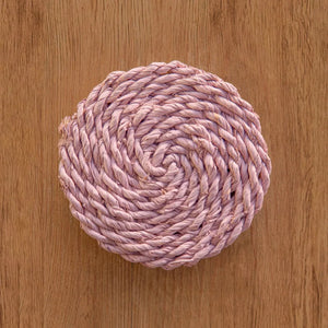 Pink woven coaster on a wooden surface.