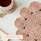 Pink woven coasters on a white surface with a cup of tea.