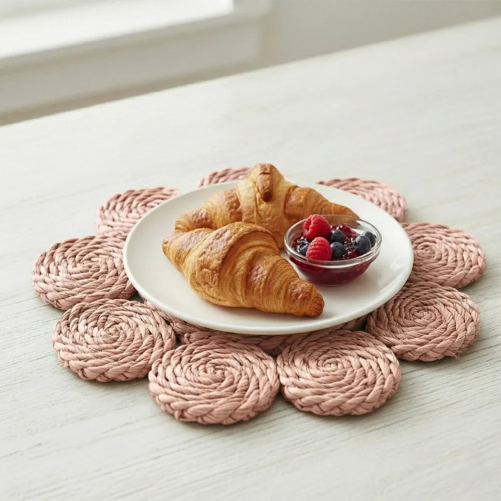 Pink woven trivets on a white surface with a plate of croissants and berries.
