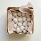 Box of powdered sugar-coated cookies with branded paper on a light background