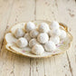 Powdered sugar-coated kahk treats on a decorative plate with a rustic wooden background