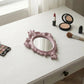 Pretty Shabby Wall Mirror Oval Chic with makeup items including pink mirror lipstick compact on white surface