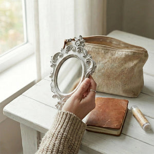 Pretty Shabby Wall Mirror Oval Chic held by person on wooden surface with notebook and pouch for home decor styling