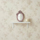 Pretty Shabby Wall Mirror – Oval Fleur displayed on a shelf against floral wallpaper