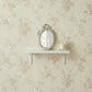 Pretty Shabby Wall Mirror – Oval Fleur displayed on a shelf against floral wallpaper