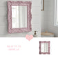 Decorative pink mirror with ornate frame in a bathroom setting